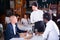 Polite asian waitress serving male guests in restaurant