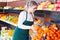 Polite female in apron selling fresh oranges