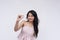 A polite young asian woman asking for a little bit more, gesturing with thumb and index finger.  on a white background