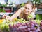 Polite young female seller holding bunch of grapes on market