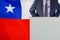 Political personality standing on the stage for conference on Chile flag background. Male speaker in Chile