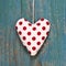 Polka dotted heart on turquoise wooden surface in country style.