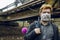 Polluted decay outdoor environment concept with male portrait in face mask and bag with pink doll in dirty outside area and rusty