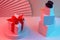 The polygonal snowman of cubes and gift is illuminated with neon light, against the background of the fan. Trend Concept 2020,