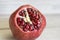 Pomegranate fruit on wooden tray with cut top part, red clusters of juicy seeds inside