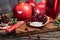 Pomegranate fruits with leaves and open pomegranates on old wooden board, dark vintage background