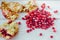 Pomegranate peel and seeds over white wooden background.