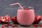 Pomegranate raspberry smoothie in a tumbler glass closeup on slate