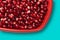 Pomegranate seeds on red heart shaped dish studio