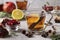 Pomegranate tea with lemon and cinnamon stick in two transparent cups on a gray concrete background, warming wellness drink