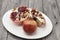 Pomegranates have broken into pieces with red berries on a porcelain plate on a dark background.