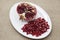 Pomegranates have broken into pieces with red berries on a porcelain plate on a textile background.