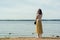 Pond beach. lonely girl in a yellow and a white blouse stands on the beach and looks into the distance.