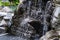 The pond below the small fountain is a sight to behold, reflecting the surrounding nature and the tranquil flow of water that