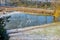 Pond with frozen water between two footpaths and wild grass covered in snow