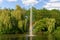 Pond, lake in the park, nature reserve, recreational area with fountain in the middle and with beautiful green trees in the backgr