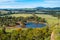 Pond and native trees among meadows and pastures.