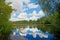 Pond with reflected clouds in the forest. Summer landscape