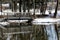 The pond`s reflection shows the snow covered footbridge.