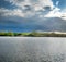 Pond before the storm and beautifully lit trees and fields in spring. weather, picturesque landscapes