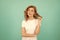 pondering redhead girl with curly hair on blue background