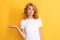 pondering redhead woman presenting product on yellow background with copy space