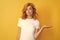 pondering redhead woman presenting product on yellow background with copy space