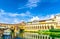 Ponte Vecchio bridge with colourful buildings houses over Arno River blue reflecting water in Florence