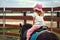 Pony riding, young girl as a horseback jockey rear view. female child as a horse rider. equestrian ride lesson for little kids.