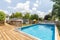 A pool in the backyard of a suburban home with a wooden deck.