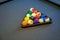 Pool billiard balls in a wooden rack on black background