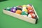 Pool billiard balls in a wooden rack, commonly used starting position, 3D illustration on green background.