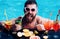 Pool party. Man swimming and drink alcohol. Summer vacation at Miami or Maldives. Cocktail with fruit at bearded man in