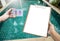 Pool tester in girl hand and blank paper clipboard over clear swimming pool water background