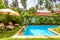 Pool with umbrella and beach beds in tropical hotel or house. Idyllic scenic courtyard