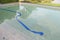 Pool is under maintenance with blue rubber hoses immersed. Change new water