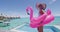 Pool Vacation Woman in bikini and inflatable pink flamingo toy float by pool