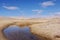 Pool of water surrounded by sand dunes.