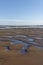 Pools of water in the sand left behind by the retreating tide at St Cyrus Nature Reserve beach