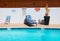 Poolside with sunbed and deckchair at outdoor pool with blue water in summer