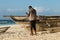 Poor African fisherman repairing his old wooden boat the ocean