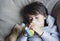 Poor boy tired from chest coughing holding inhaler mask, Child falling a sleep while using the volumtic for breathing treatment,