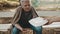 Poor elderly homeless man counting left coins in the park and receiving charity meal