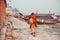 Poor lonely man walking past famous Ganges river with rustic riverboats