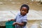 Poor malagasy boy carrying plastic water bucket