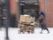 Poor man pulling a cart with cardboard in the city in snowy winter day