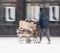 Poor man pulling a cart with cardboard in the city in snowy winter day