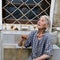 Poor old Bulgarian woman with walking cane and worn out, shabby dress sitting on stairs on the street of Varna