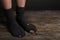Poor person in shabby socks on wooden floor