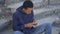 Poor young man counting money sitting alone city stairs, low living standard